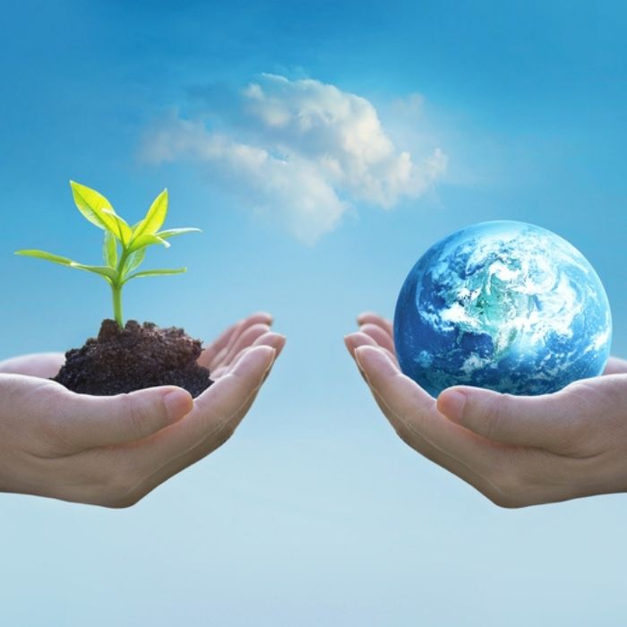Photo of blue skies and two hands. One holding the world and the other holding a seedling in dirt