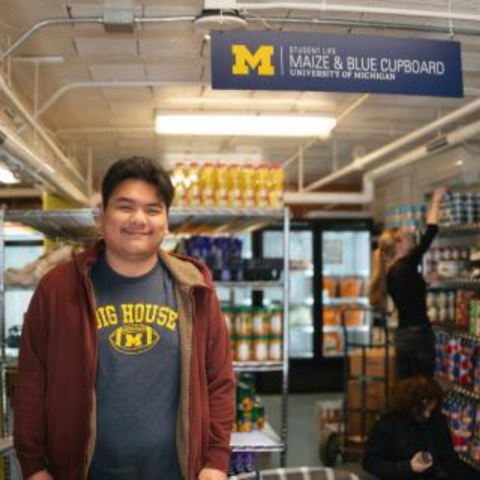 Reza (Ray) Azizan standing in front of the Maize and Blue Cupboard